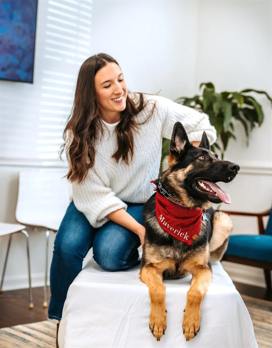 Animal wellness Dr. Megan applying controlled pressure to the rear spine of a German Shepherd during an in-office session